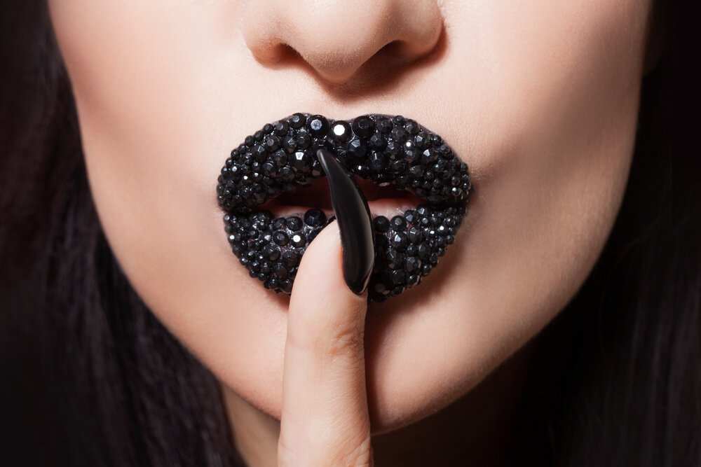 Women's lips with black lipstick and rhinestones make tin Shhh. Black lipstick and black and white manicure